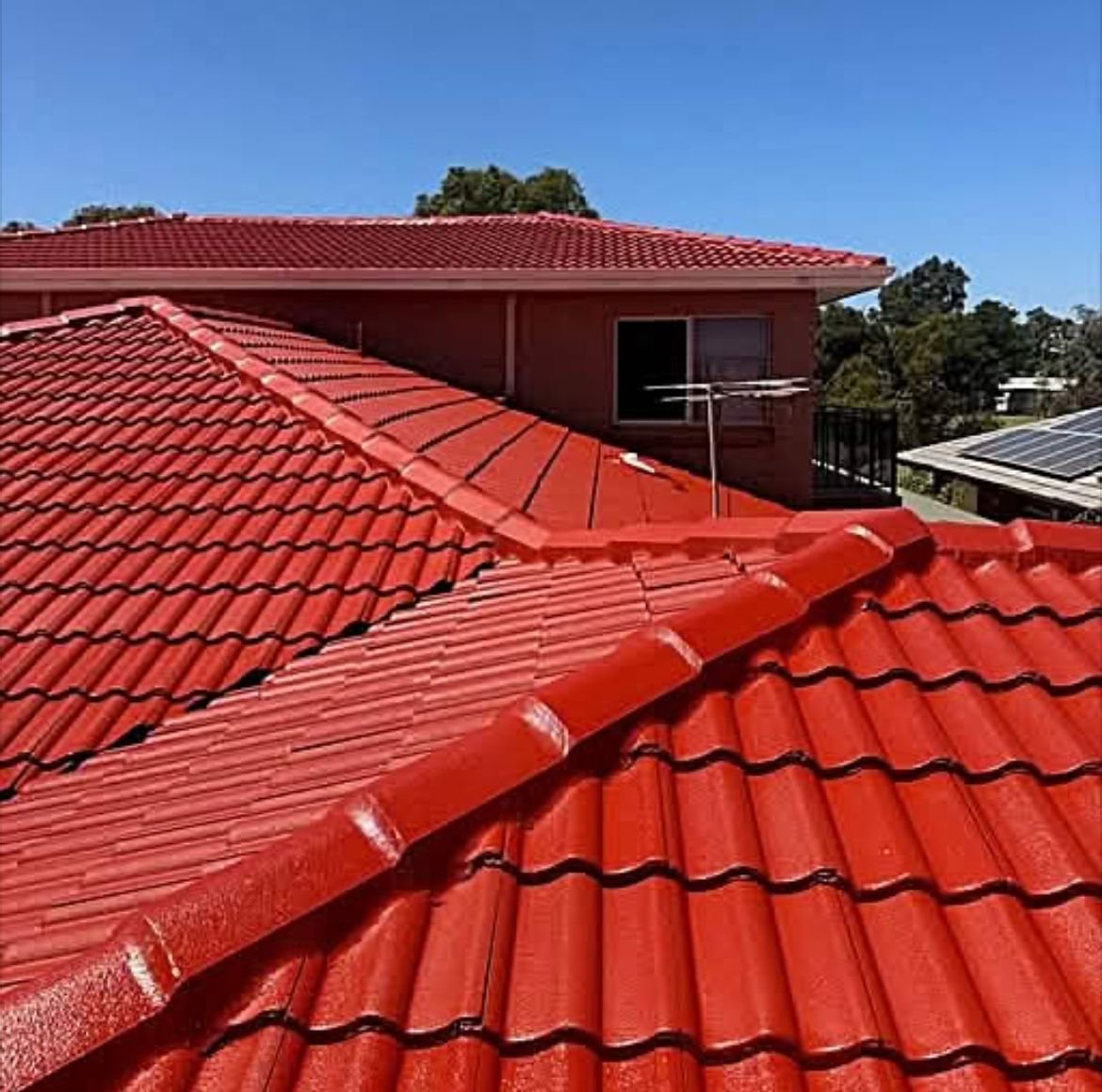 Close-up of a tile roof freshly sealed and painted in deep terracotta