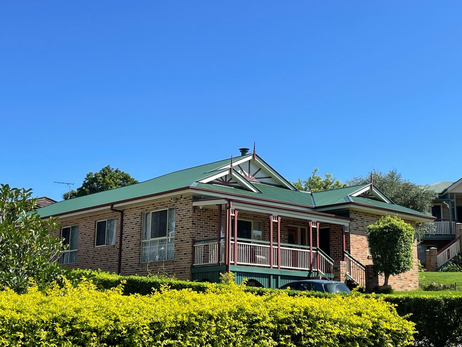 Brick home with a restored green metal roof and painted fascia
